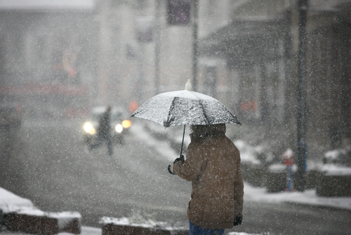 man-holding-umbrella-in-street-in-snow